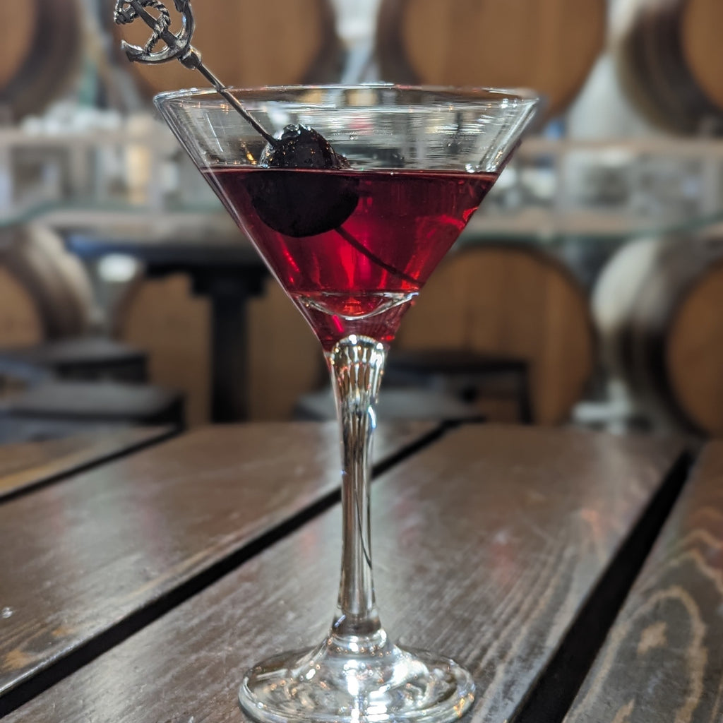 Manhattan cocktail made with Tofino West Coast Whiskey, served in martini glass garnished with cherry on a cocktail pick adorned with an anchor